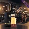 Maison Alhambra Smoky Touch 80ml EDP — A perfume bottle and its box are placed in the foreground of a gym with a man lifting weights in the background. | Maison Alhambra Smoky Touch 80ml EDP — Botol minyak wangi dan kotaknya diletakkan di latar depan gimnasium dengan seorang lelaki mengangkat berat di latar belakang.