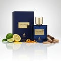 Maison Alhambra Spectrum Eau de Parfum — A blue glass perfume bottle with a gold cap stands next to its navy blue box, surrounded by citrus slices, orange zest, and wood pieces on a reflective white surface. | Maison Alhambra Spectrum Eau de Parfum — Botol kaca biru dengan penutup emas berdiri di sebelah kotak biru