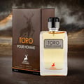 Maison Alhambra Toro Pour Homme — A clear glass perfume bottle with yellow liquid and a silver cap sits next to its brown cardboard box featuring a stag silhouette. | Maison Alhambra Toro Pour Homme — Botol kaca jernih dengan cecair kuning dan penutup perak terletak di sebelah kotak kadbod coklatnya yang menampilkan