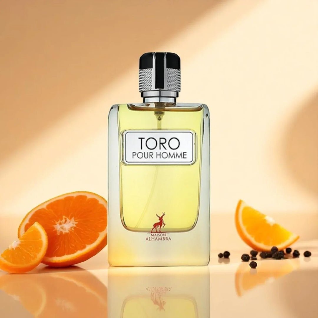 Maison Alhambra Toro Pour Homme – A clear glass bottle of yellow liquid perfume with a silver cap, placed on a reflective surface with sliced oranges and peppercorns. | Maison Alhambra Toro Pour Homme – Botol kaca jernih berisi minyak wangi kuning dengan penutup perak, diletakkan di permukaan reflektif bersama hirisan