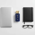 Maison Alhambra True Word by Maison Alhambra 100ml EDP — A blue perfume bottle with a gold cap sits between a silver laptop and a black notebook, with black glasses below. | Maison Alhambra True Word by Maison Alhambra 100ml EDP — Botol minyak wangi biru dengan penutup emas terletak di antara komputer riba perak dan