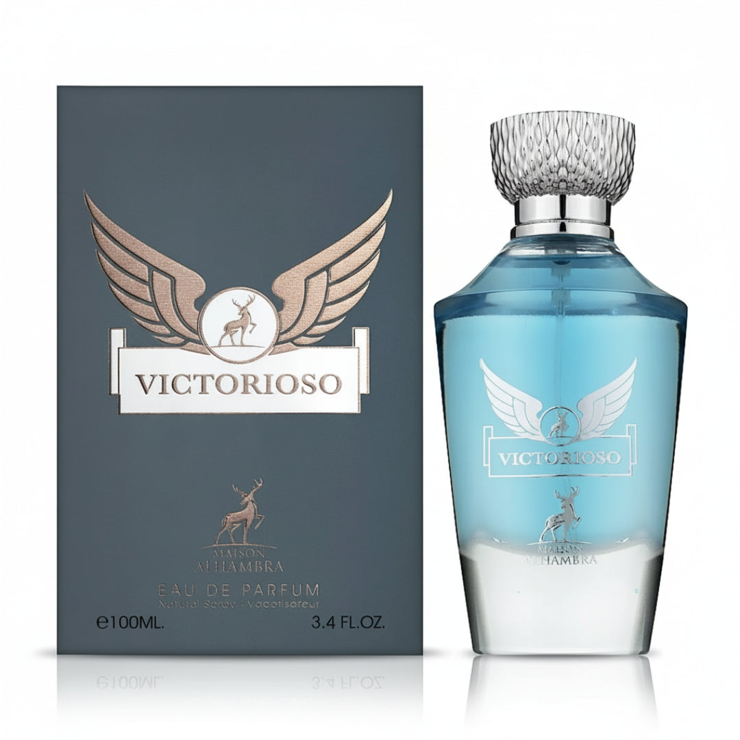 Maison Alhambra Victorioso by Maison Alhambra 100ml EDP Men — A dark grey box with gold wings and a deer logo stands next to a clear glass perfume bottle with blue liquid and a silver cap, featuring matching gold wings and deer logo. | Maison Alhambra Victorioso by Maison Alhambra 100ml EDP Men — Kotak kelabu gelap