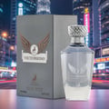 Victorioso by Maison Alhambra 100ml EDP Men — A grey box and a clear glass perfume bottle with a silver cap are displayed against a blurred, brightly lit cityscape at night. The box and bottle feature a winged emblem and a deer graphic. | Victorioso by Maison Alhambra 100ml EDP Men — Kotak kelabu dan botol minyak