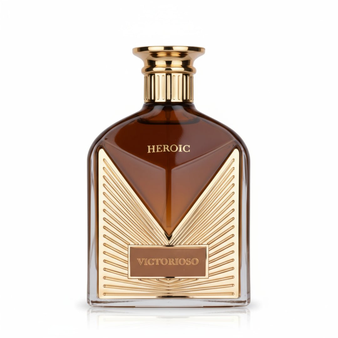 Maison Alhambra Victorioso Heroic — A brown glass perfume bottle with gold accents and the word HEROIC embossed on the front, set against a white background. | Botol minyak wangi kaca perang Maison Alhambra Victorioso Heroic dengan perincian emas dan perkataan HEROIC tertera di hadapan, berlatarkan putih.