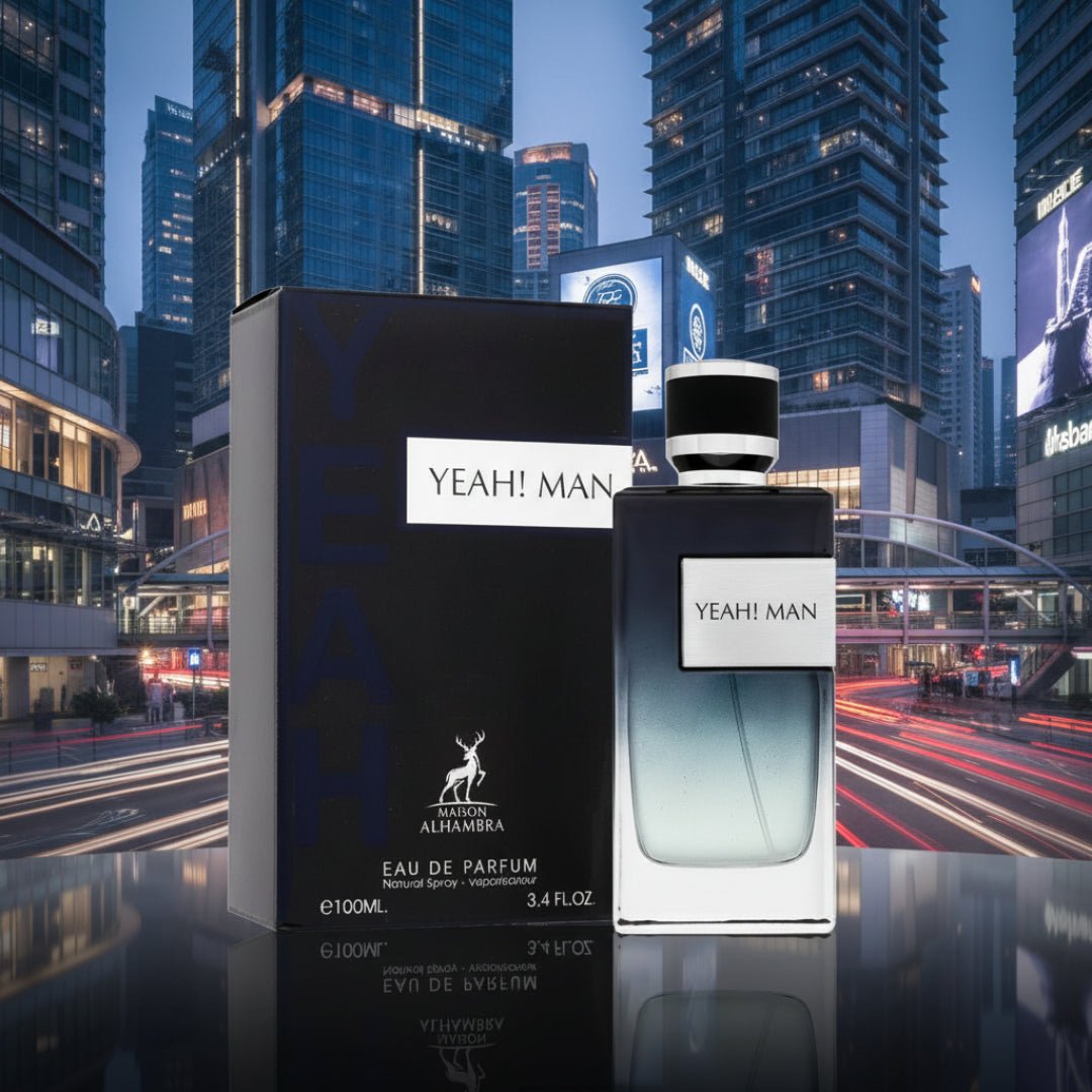 Maison Alhambra Yeah by Maison Alhambra 100ml EDP Men — A perfume bottle and its box are displayed in front of a blurred cityscape at night with light trails from cars. | Maison Alhambra Yeah by Maison Alhambra 100ml EDP Men — Botol minyak wangi dan kotaknya dipamerkan di hadapan latar bandar yang kabur pada waktu