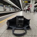 Yeah! by Maison Alhambra — A dark blue perfume box sits inside an open grey tote bag on a subway platform, with train tracks and station lights in the background. | Yeah! oleh Maison Alhambra — Kotak minyak wangi biru gelap diletakkan di dalam beg tote kelabu yang terbuka di platform stesen kereta bawah tanah, dengan