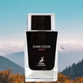 Maison Alhambra Dark Door Sport Men 100ml EDP — A clear glass perfume bottle with a black label featuring white text and a deer logo, set against a misty mountain landscape with orange foliage in the foreground. | Maison Alhambra Dark Door Sport Men 100ml EDP — Botol minyak wangi kaca jernih dengan label hitam